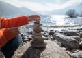 person stacking rocks by the lake