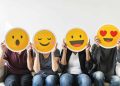 four people hold happy emoji masks