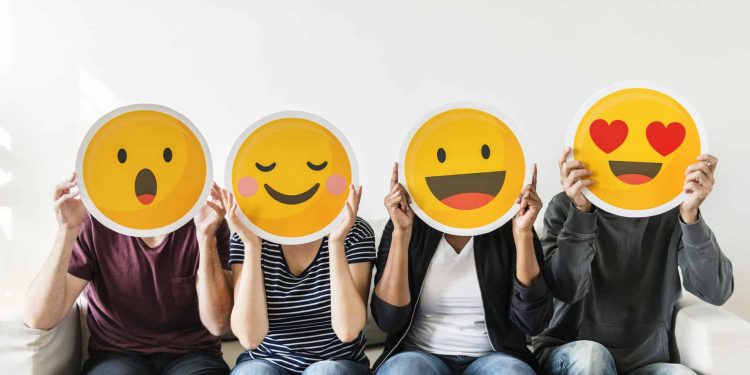 four people hold happy emoji masks