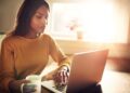 Woman checking her computer and holding coffee cup