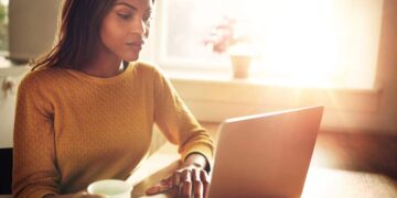 Woman checking her computer and holding coffee cup