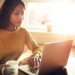 Woman checking her computer and holding coffee cup