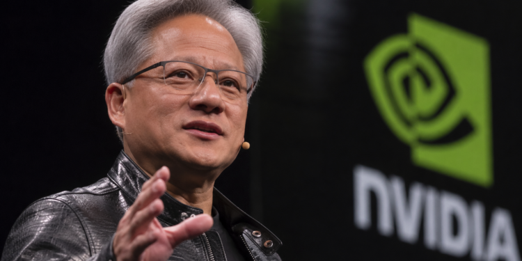 Jensen Huang speaks on stage beside a large Nvidia logo during a technology event.