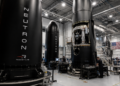 Rocket Lab engineers work around Neutron rocket hardware inside a large assembly facility.