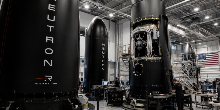 Rocket Lab engineers work around Neutron rocket hardware inside a large assembly facility.