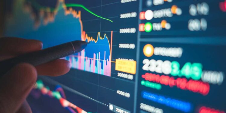Financial analyst reviews numbers and charts on a screen