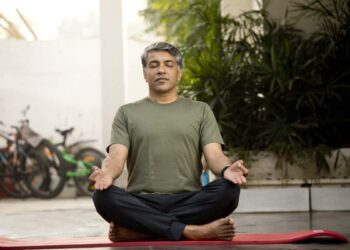 Man meditating in lotus position outdoor on patio
