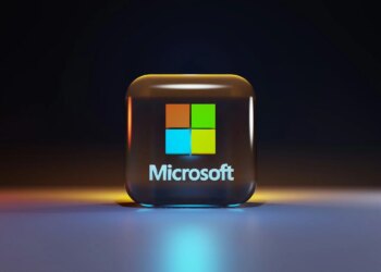 A glossy glass cube with the Microsoft logo on a dark surface