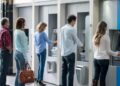 Group of people in a line at an ATM waiting to make a cash withdrawal