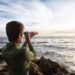 person with spyglass looks at ocean horizon